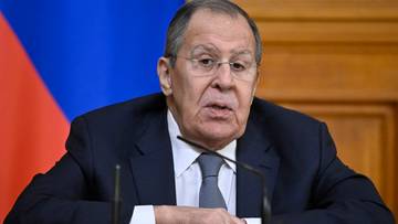 Siergiej Ławrow, minister spraw zagranicznych Rosji, siedzi przy stole, mówi do mikrofonu.