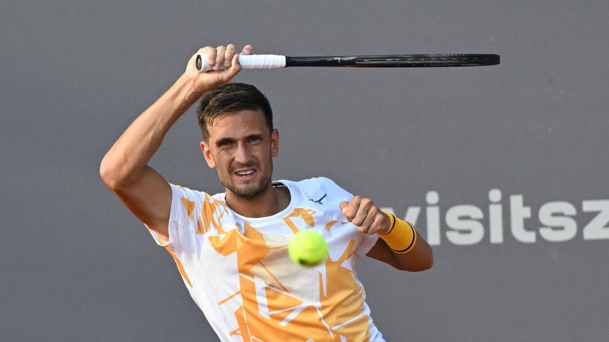 Gracz tenisa odbija piłkę rakietą, skupiony na zagraniu.