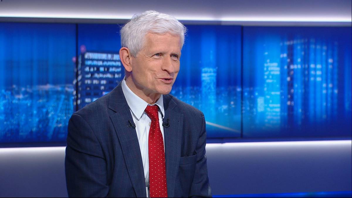 Profesor Roman Kuźniar, w granatowej marynarce i czerwonym krawacie, wypowiada się w studiu telewizyjnym.