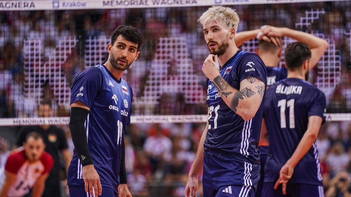 Siatkarze w niebieskich strojach przed siatką podczas meczu.