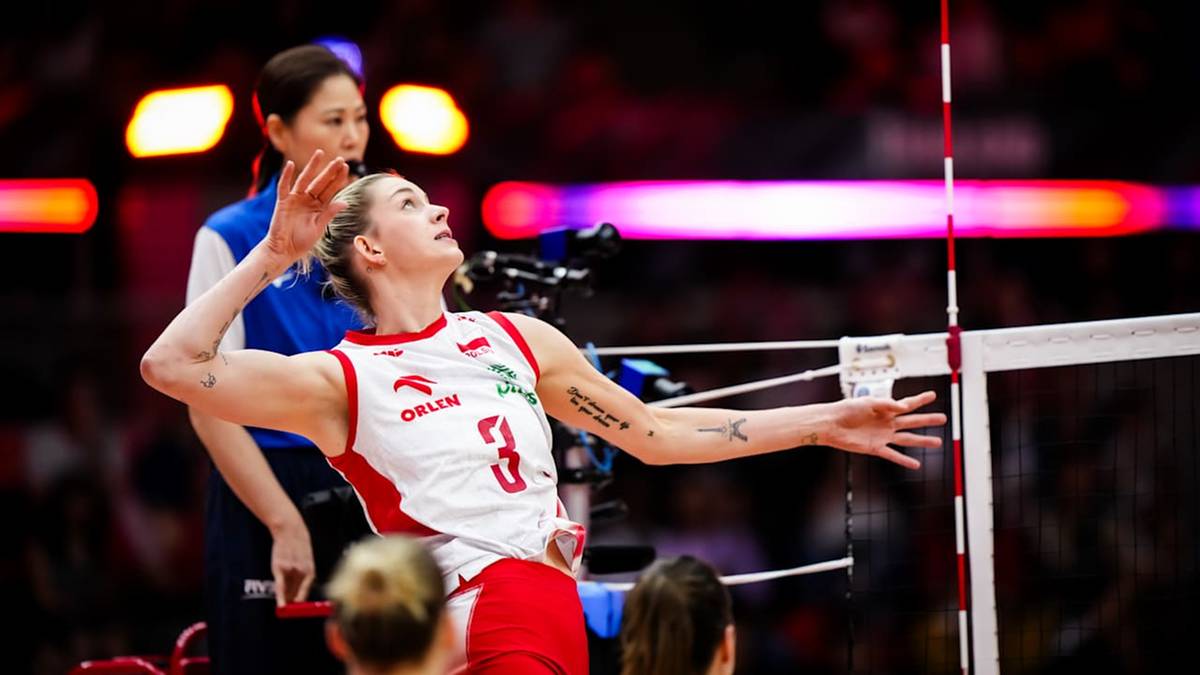 Zawodniczka w białej koszulce z numerem 3 i czerwonymi wstawkami, grająca w siatkówkę. Wykonuje zagrywkę. Na drugim planie inna zawodniczka.