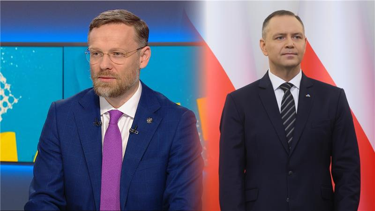 Dwaj mężczyźni w garniturach, jeden siedzi i m&oacute;wi, drugi stoi.