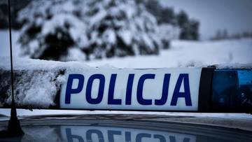 Napis POLICJA na taśmie policyjnej pokrytej śniegiem.