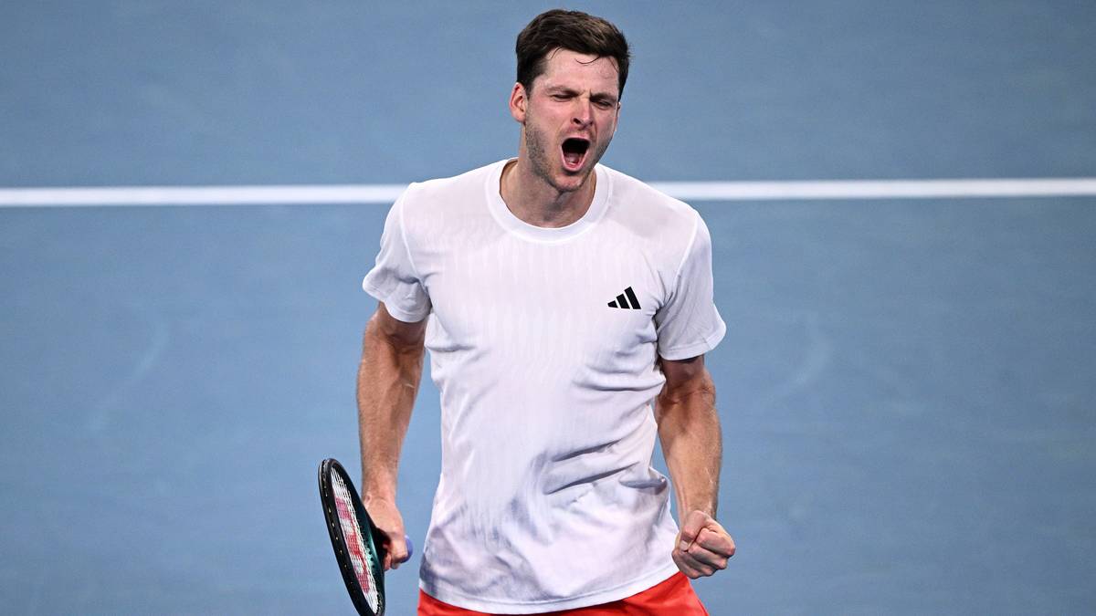 Hubert Hurkacz, polski tenisista, z wyrazem triumfu na twarzy, trzymający rakietę tenisową.