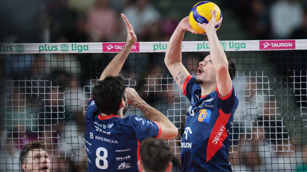 Siatkarz podczas zagrywki, jego kolega z drużyny asekuruje go.