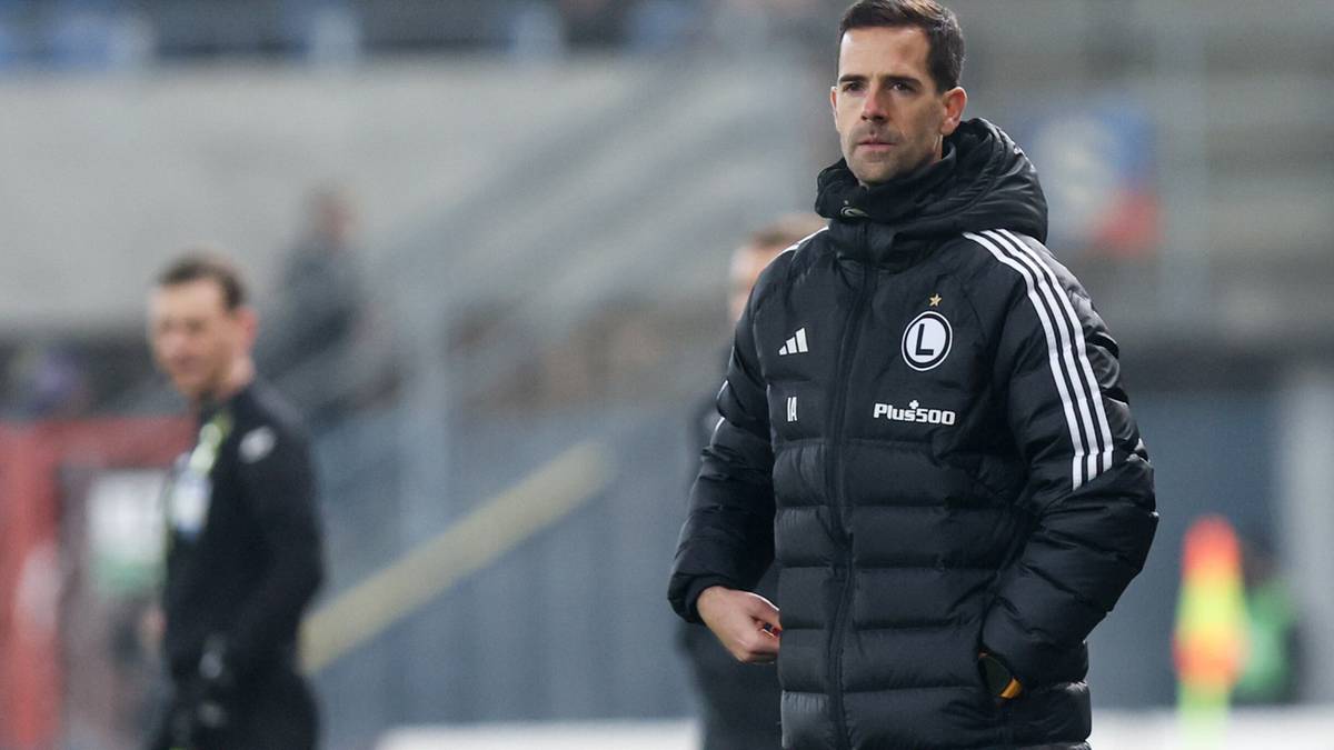 Trener w czarnej kurtce z logo Legii Warszawa.