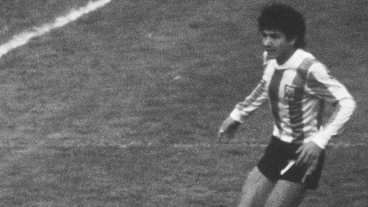 Piłkarz w koszulce z pasami, w ruchu na boisku.