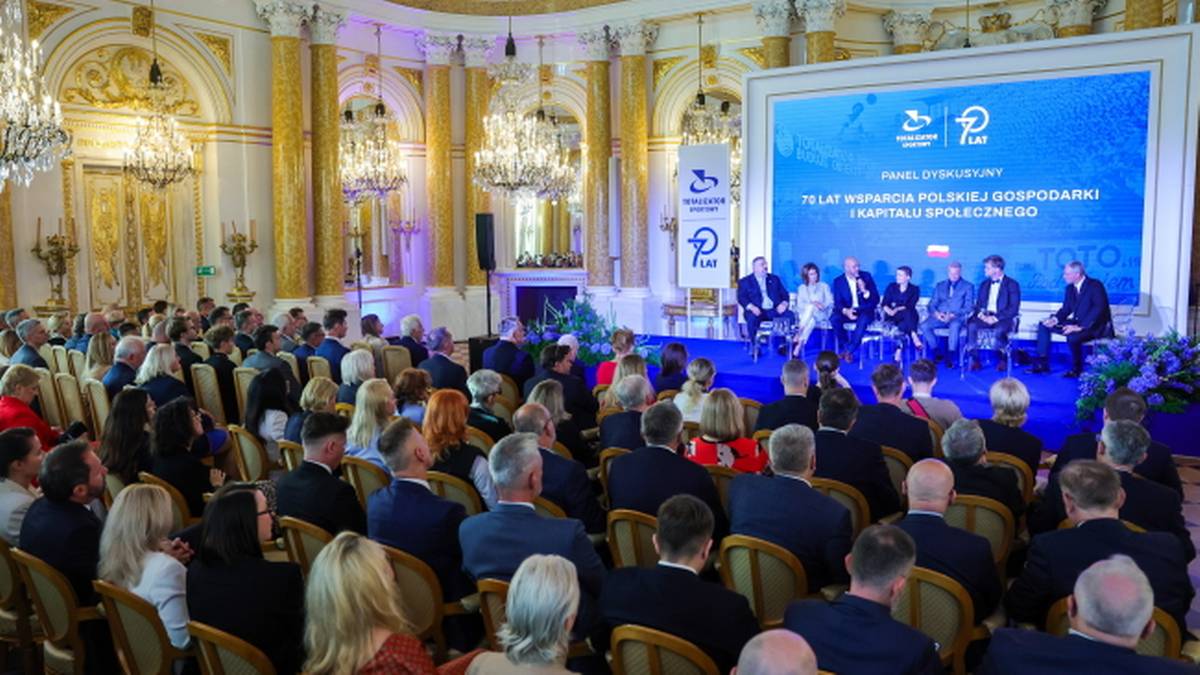 Uczestnicy siedzą na krzesłach w udekorowanej sali podczas uroczystości z okazji 70-lecia Totalizatora Sportowego.