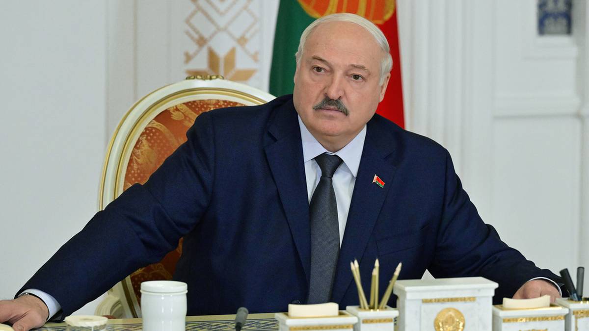 Aleksandr Łukaszenka, prezydent Białorusi, siedzi przy biurku w garniturze.