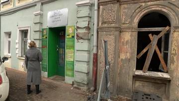 Budynek fundacji z zielonymi drzwiami i kobietą stojącą przed wejściem.