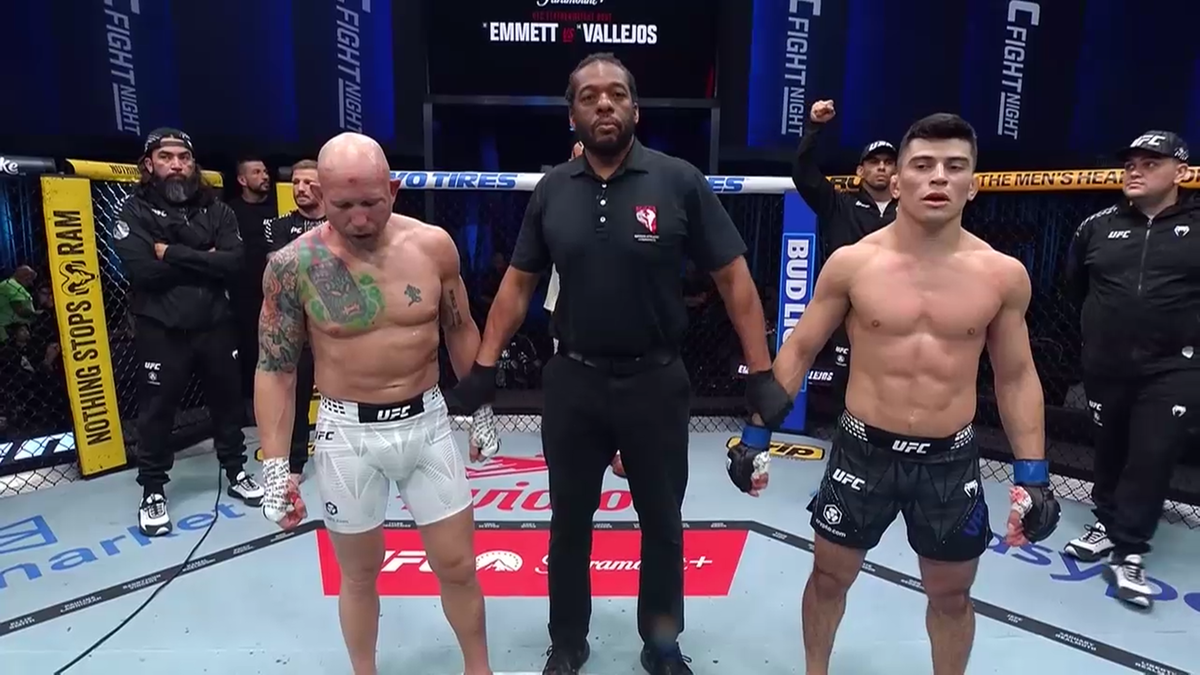 Dwóch zawodników MMA, Josh Emmett i Kevin Vallejos, stoi w oktagonie po walce, trzymając się za ręce, z sędzią pośrodku.