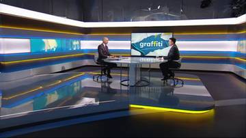 Dw&oacute;ch mężczyzn siedzi naprzeciwko siebie przy okrągłym stole w nowoczesnym studiu telewizyjnym. Na ekranie za nimi widnieje logo programu "graffiti".