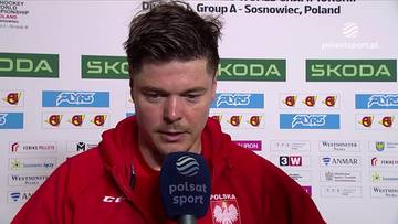Hokeista Aron Chmielewski w czerwonej bluzie z orłem na piersi, trzymający mikrofon Polsatu Sport.