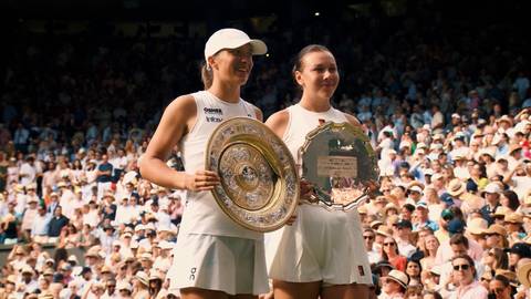 Dwie tenisistki na korcie wimbledońskim z trofeami.