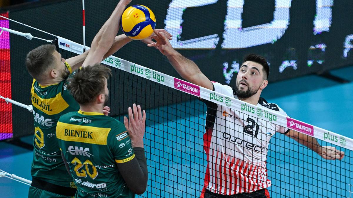 Siatkarze w akcji nad siatką podczas meczu siatk&oacute;wki.