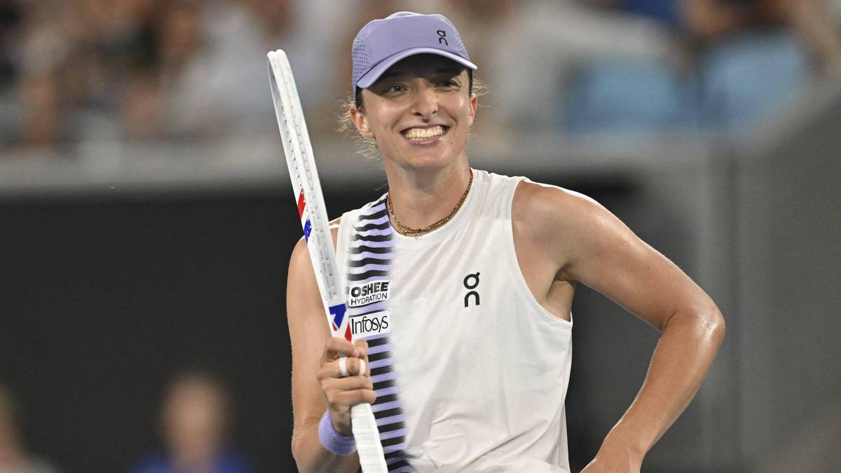 Uśmiechnięta kobieta w czapce i sportowym topie trzyma rakietę tenisową.