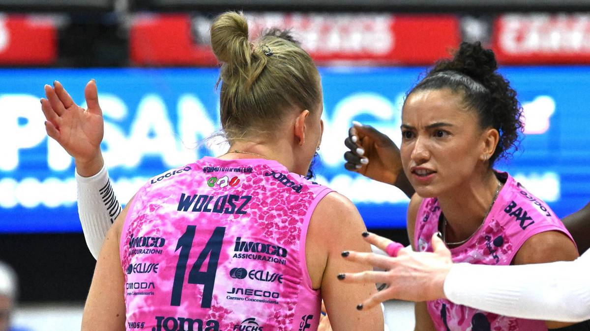 Dwie siatkarki w r&oacute;żowych strojach sportowych rozmawiają na boisku siatkarskim.