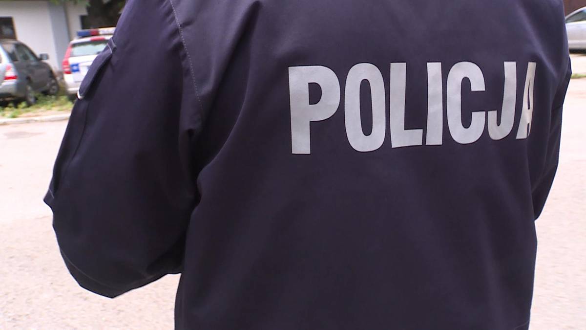 Fragment pleców policjanta w granatowej kurtce z napisem POLICJA.