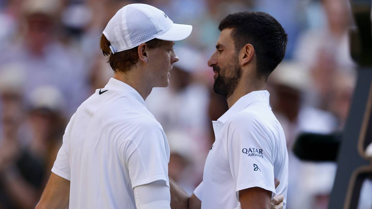 Dwóch tenisistów, Jannik Sinner i Novak Djoković, w białych strojach sportowych, patrzą na siebie podczas meczu.