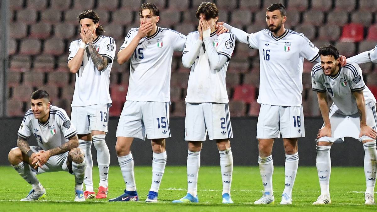 Piłkarze reprezentacji Włoch w białych strojach stoją na murawie stadionu, z wyrazem głębokiego rozczarowania na twarzach. Niekt&oacute;rzy zasłaniają dłoniemi twarze, inni patrzą w ziemię, emanując smutkiem po porażce.