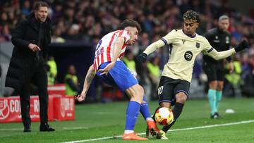 Dw&oacute;ch piłkarzy walczy o piłkę na boisku, jeden w koszulce Atletico Madryt, drugi w koszulce FC Barcelony.