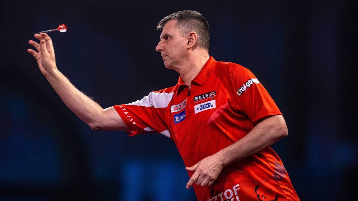 Gracz darta w czerwonej koszulce przygotowuje się do rzutu lotką.