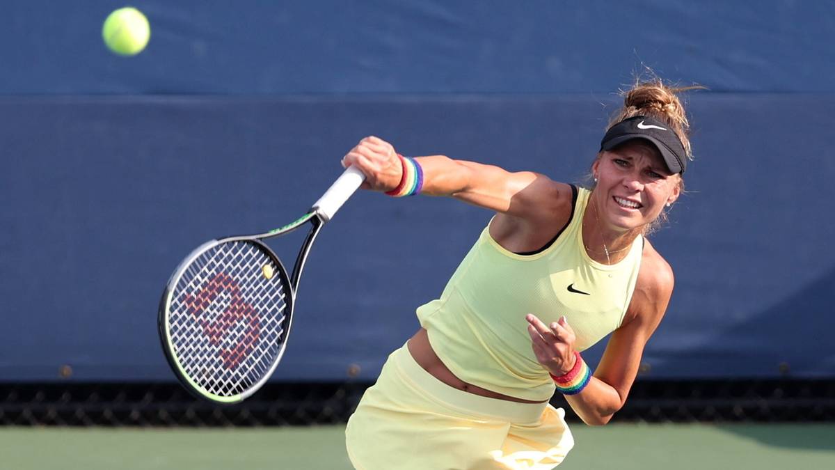 Polka tenisistka serwuje piłkę, w żółtej koszulce i spódnicy, podczas meczu.