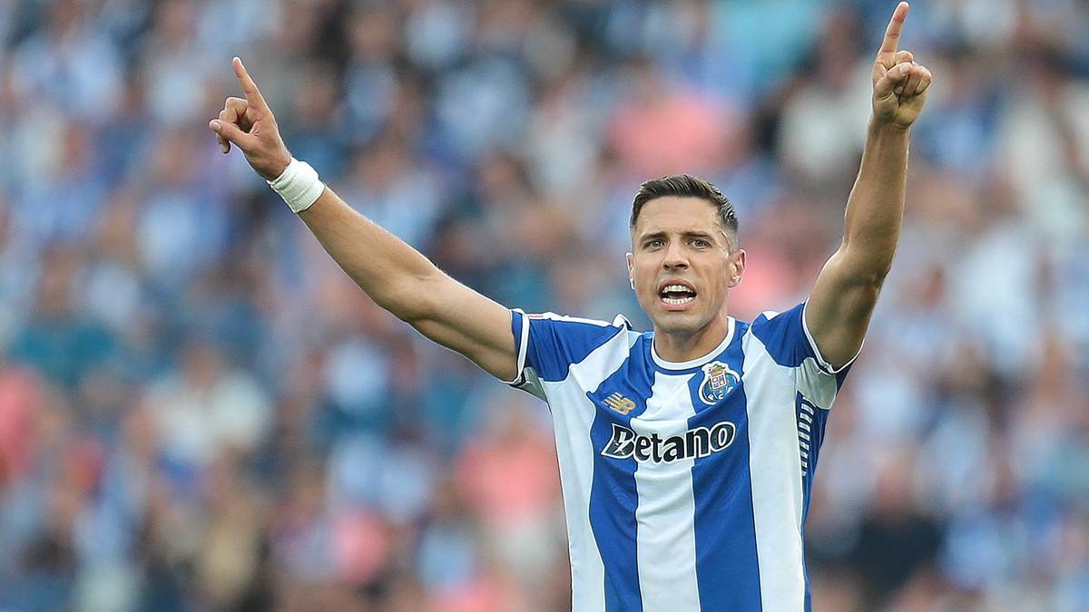 Piłkarz w koszulce FC Porto z rękami w górze i uniesionymi palcami wskazującymi, celebrujący bramkę.