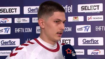 Filip Michałowicz podczas wywiadu na tle ścianki sponsorskiej.