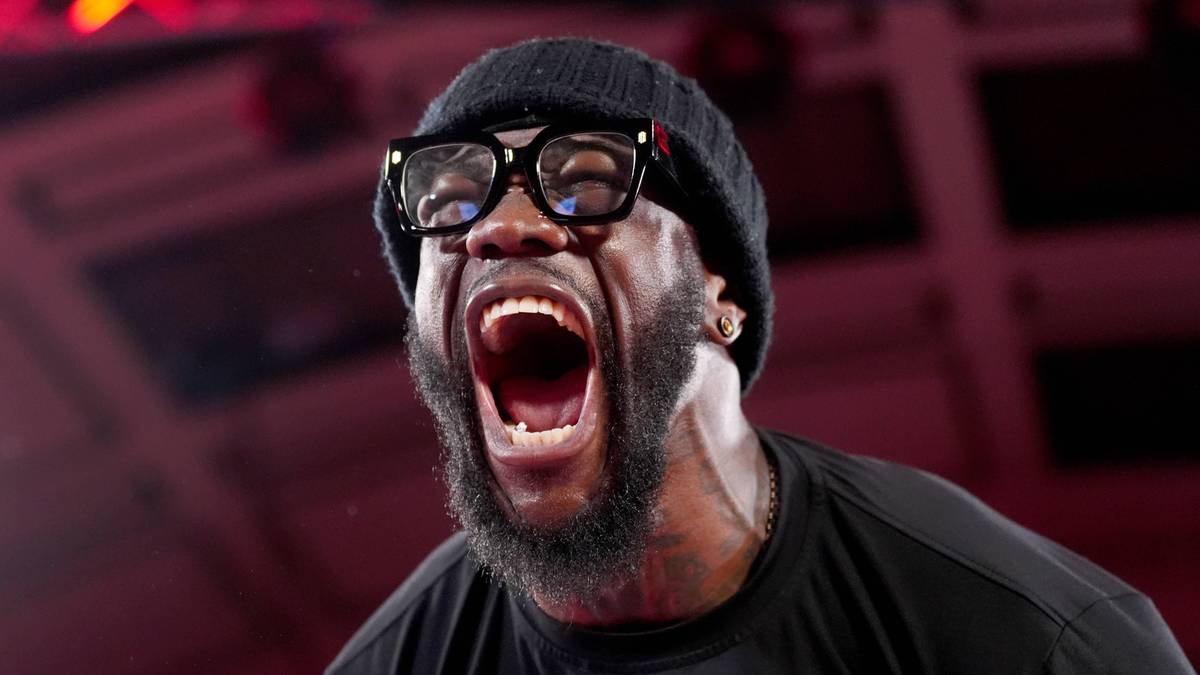Bokser Deontay Wilder krzyczy z emocji w trakcie walki, nosząc czarną czapkę i okulary.