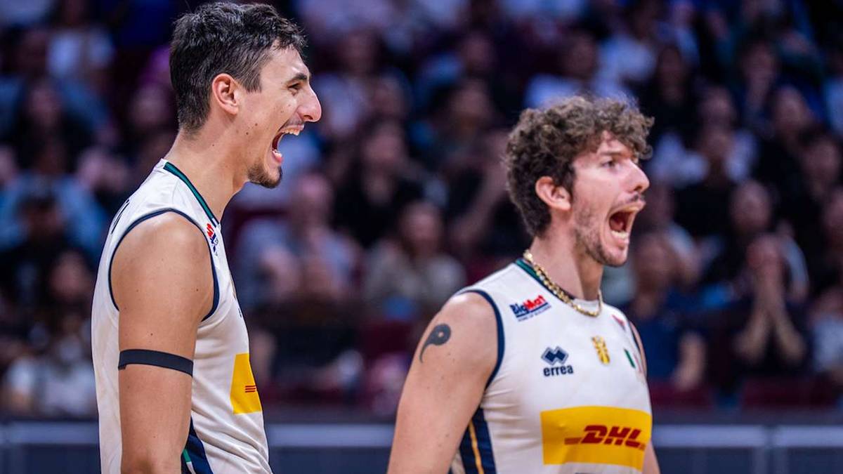 Dwóch siatkarzy w białych strojach z żółtymi wstawkami i logiem "DHL" okrzykuje na boisku.