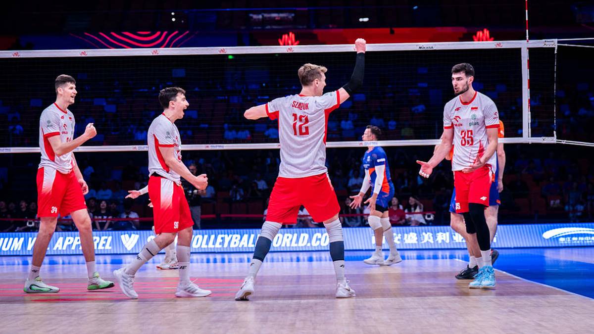 Drużyna siatkarzy Polski świętuje zdobycie punktu w meczu przeciwko Holandii. Siatkarze w białych koszulkach z czerwonymi elementami i czerwonych spodenkach celebrują sukces, jeden z nich unosi ręce w geście radości.