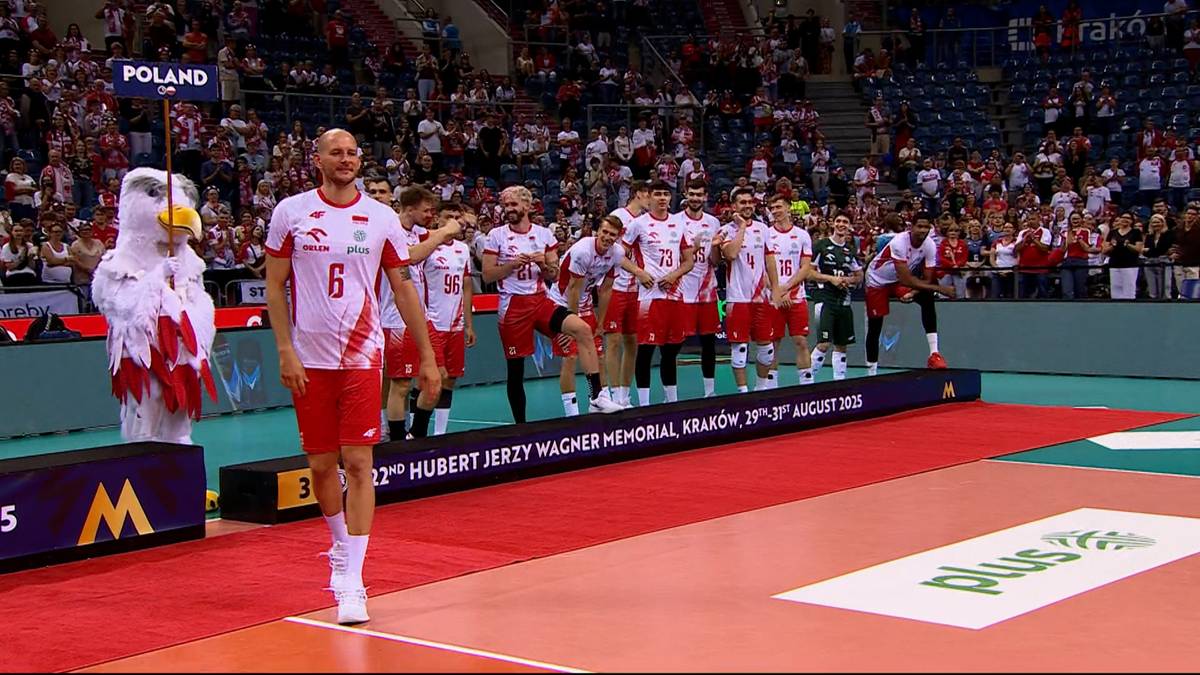 Siatkarz Bartosz Kurek na tle swojej drużyny i tłumu kibiców, wchodzący na boisko.