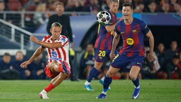 Dw&oacute;ch piłkarzy podczas meczu, jeden w stroju Atletico Madryt, drugi w stroju FC Barcelony, walczy o piłkę na boisku.