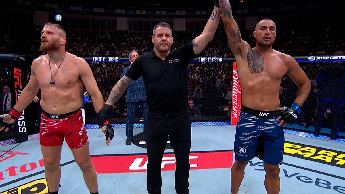 Dwóch zawodników MMA i sędzia po walce, jeden z zawodników wygrywa.