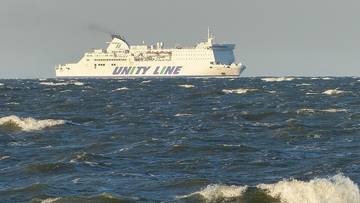 Biały prom Unity Line płynący po wzburzonym, ciemnym morzu.