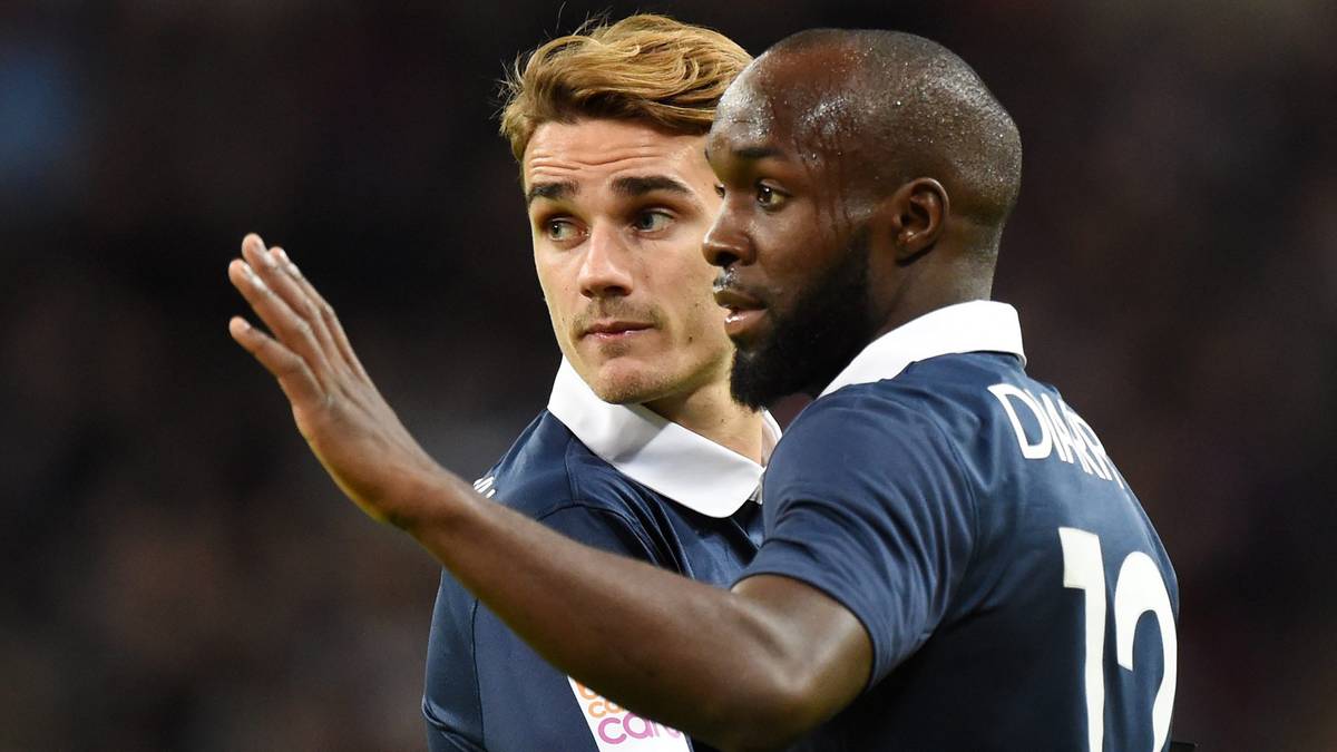 Dwóch piłkarzy w niebieskich koszulkach, jeden z nich podnosi dłoń.