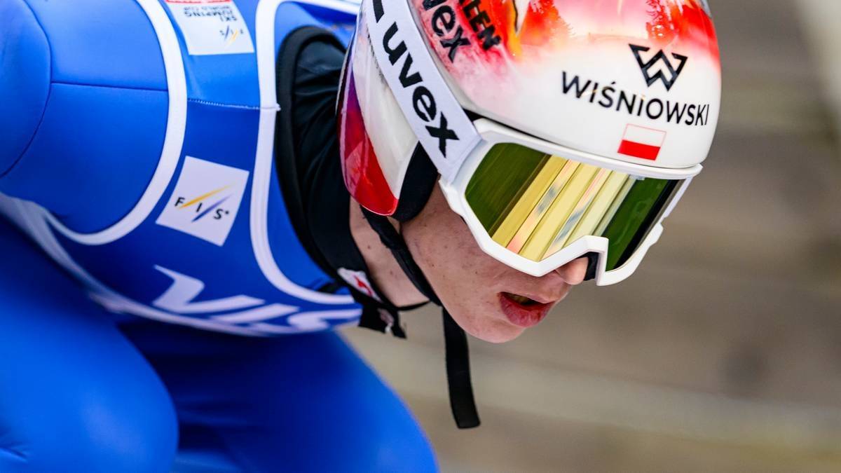 Skoczek narciarski w kasku i goglach.