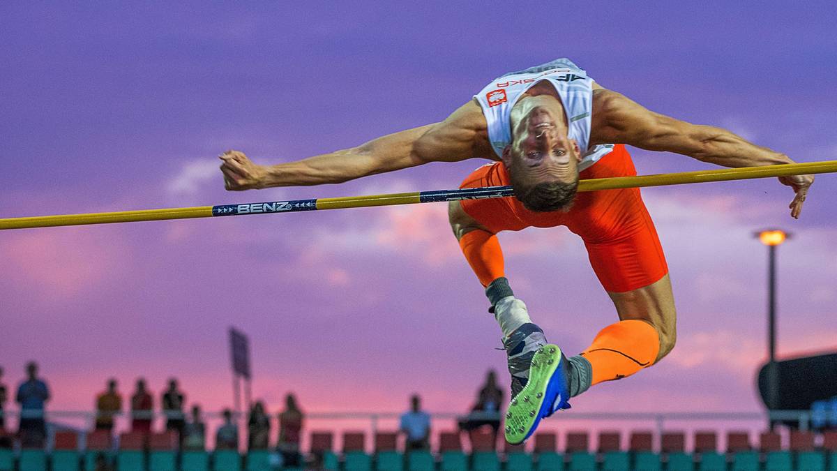Zawodnik skacze wzwyż, pokonując poprzeczkę.