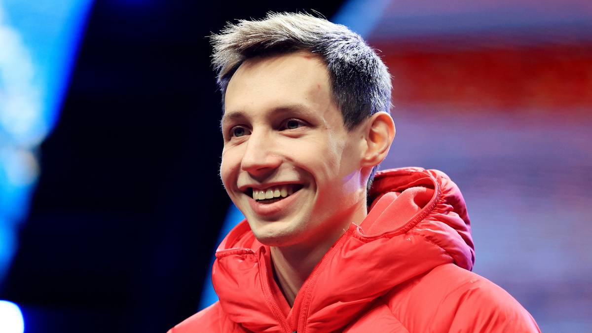 Uśmiechnięty mężczyzna w czerwonej kurtce sportowej.