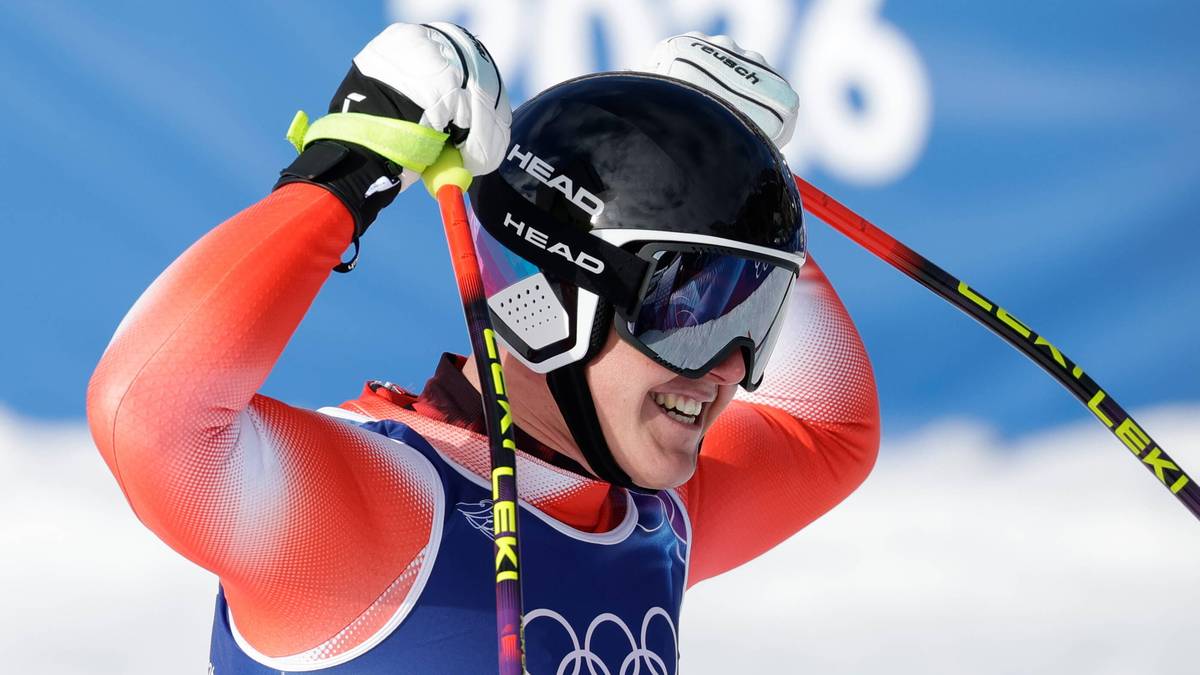 Narciarz alpejski w kasku i goglach, z kijami narciarskimi, świętuje zwycięstwo.