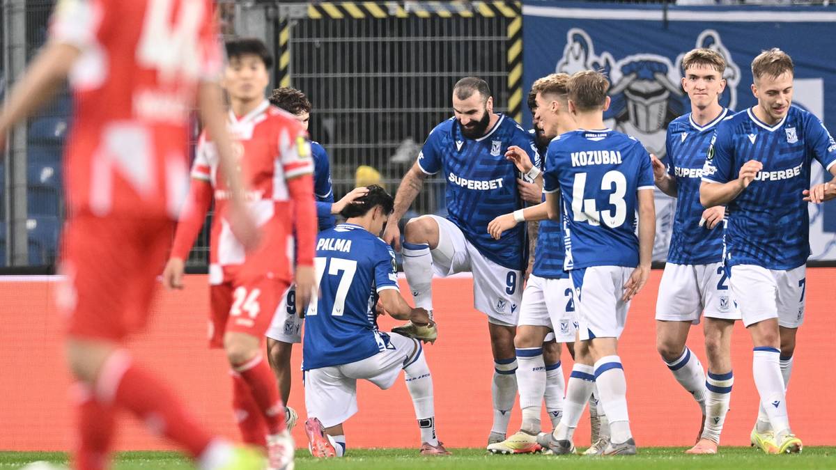 Piłkarze drużyny w niebieskich strojach świętują bramkę, jeden z nich klęczy na boisku.