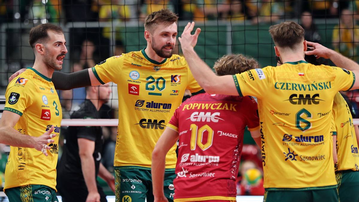 Siatkarze w żółtych strojach świętują zwycięstwo na boisku, jeden z nich podnosi rękę do góry.