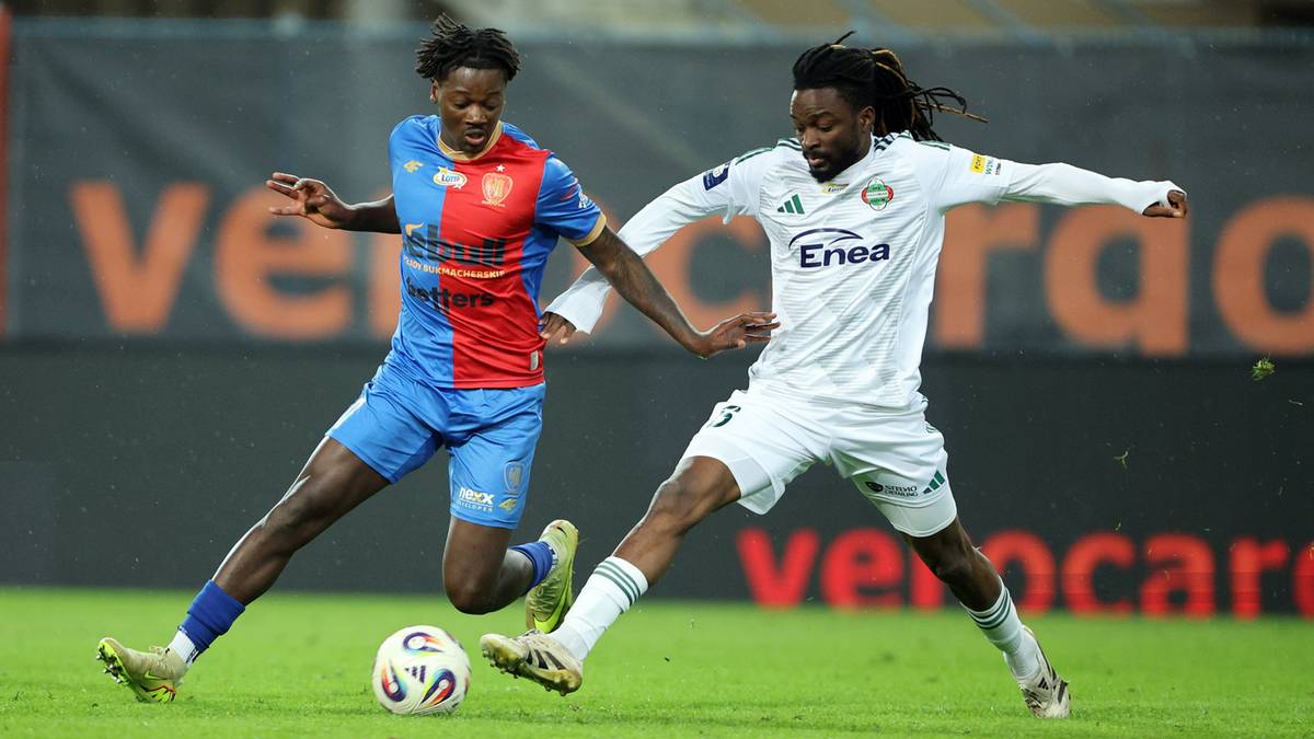 Dwóch piłkarzy walczących o piłkę na boisku podczas meczu piłkarskiego.