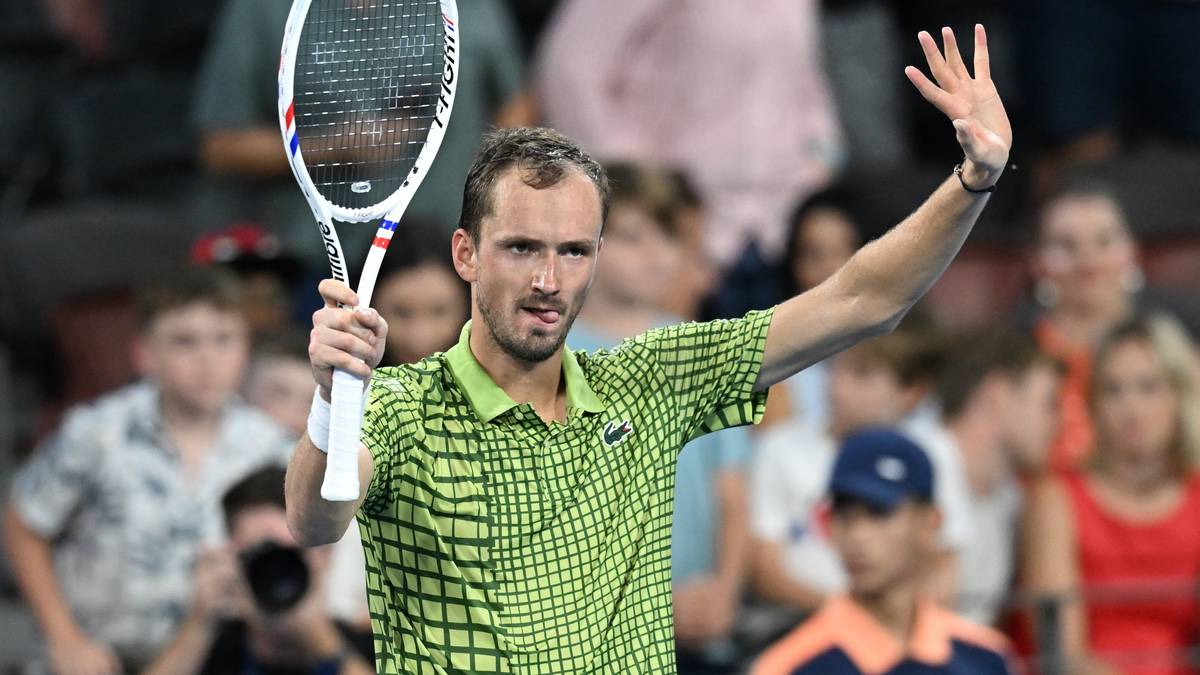 Tenisista Daniił Miedwiediew z rakietą w dłoni, unoszący drugą rękę w geście pozdrowienia.