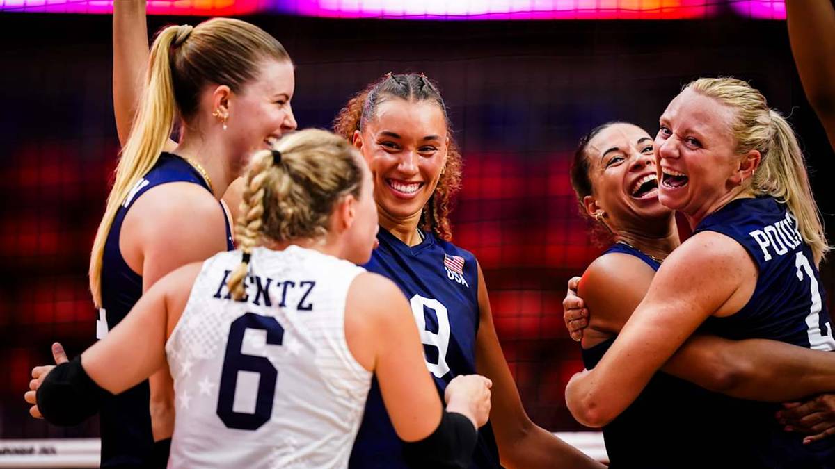 Grupa siatkarek w niebieskich strojach radośnie świętuje sukces, przytulając się i śmiejąc.