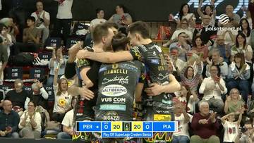 Trzech siatkarzy w czarnych strojach przytulających się na boisku podczas meczu, jeden z nich trzyma ręce na ramionach pozostałych dw&oacute;ch. Na ekranie widoczne są wyniki.