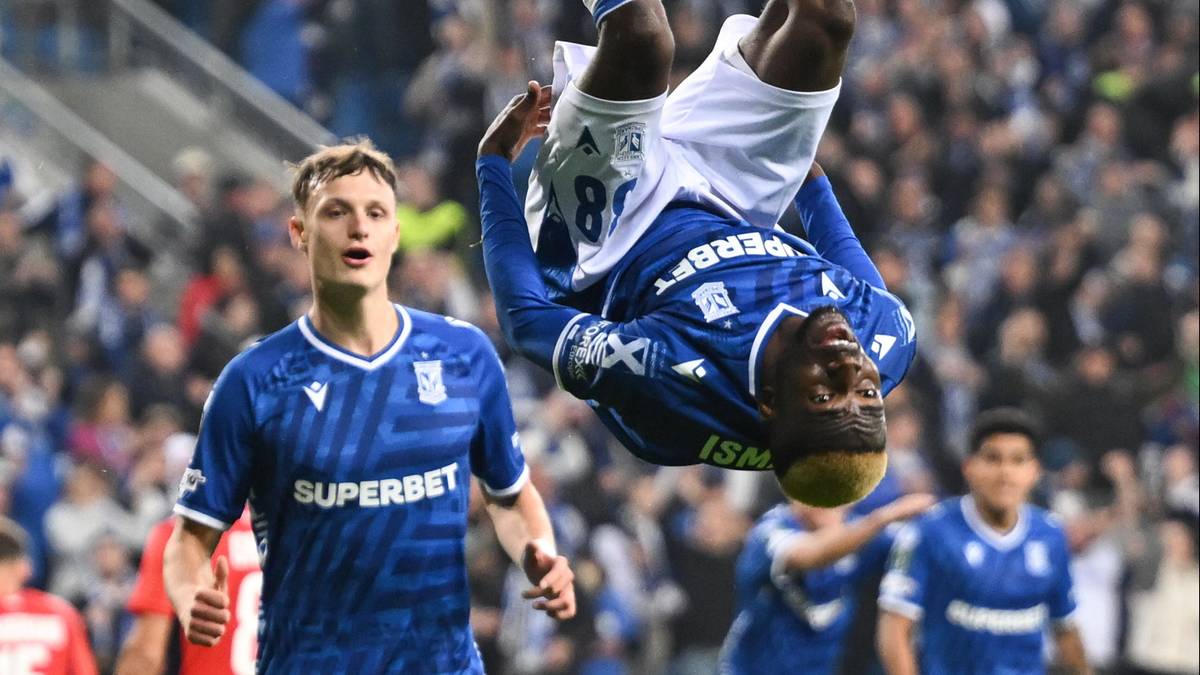 Piłkarz Lecha Poznań wykonuje salto po zdobyciu bramki, podczas gdy inny zawodnik patrzy na niego z radością.