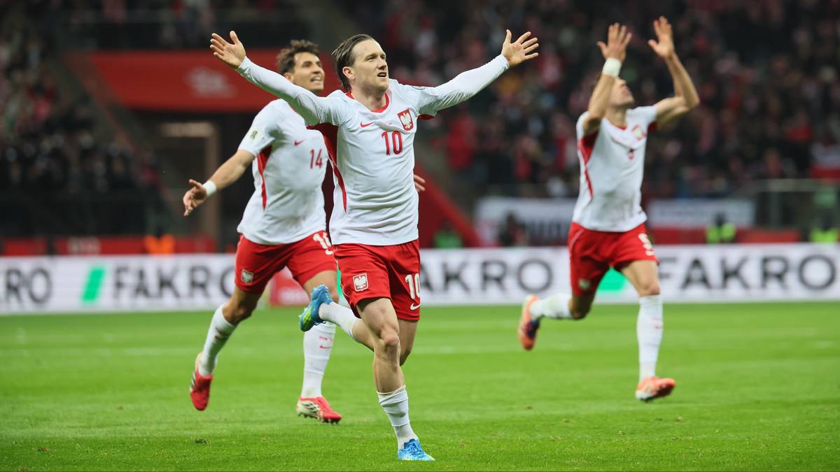 Trzej piłkarze reprezentacji Polski w białych strojach świętują na boisku.