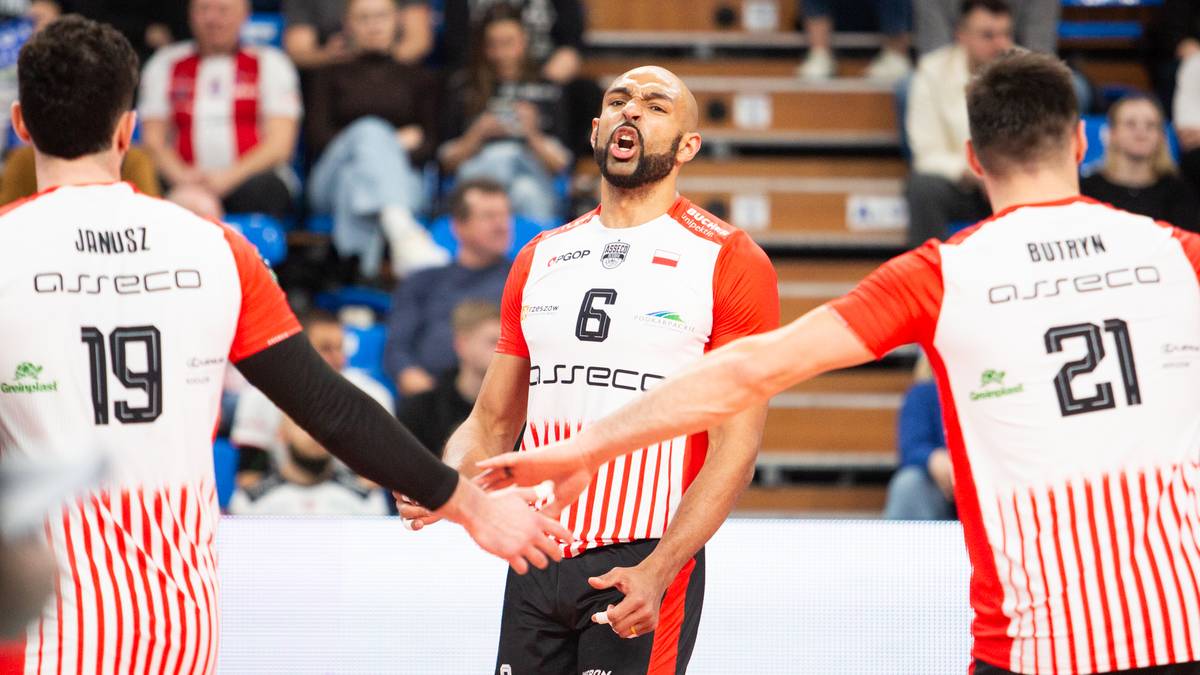 Siatkarze w białych i czerwonych strojach celebracji w środku boiska, jeden z nich trzyma rękę na sercu.